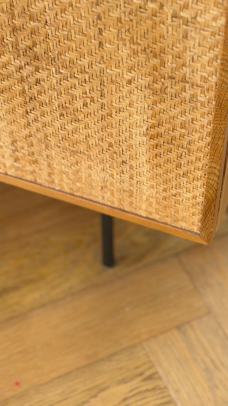 Détail d'une enfilade en cannage tressé posée sur un parquet en point de Hongrie