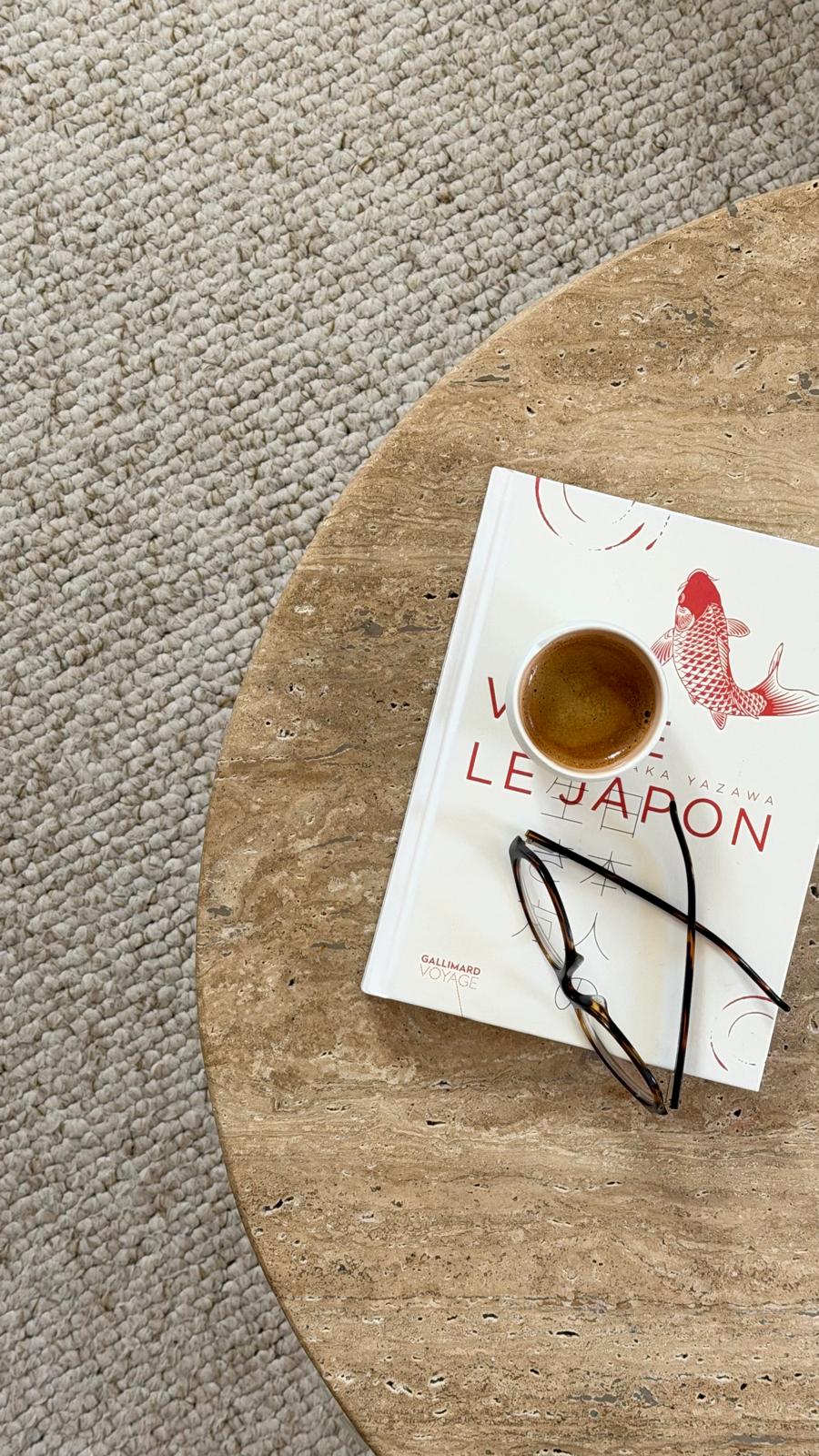 Vue de dessus d'une table en travertin, tasse de café, livre et lunettes