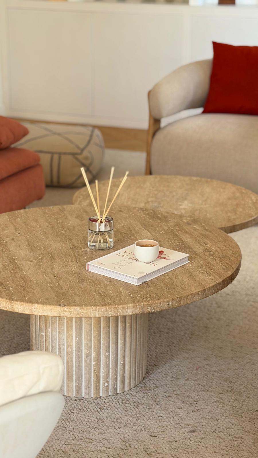 Deux tables gigognes rondes en travertin cannelé sur un tapis en laine bouclée